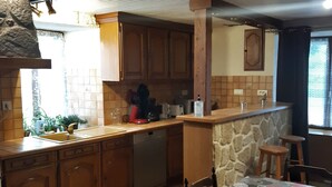 Une cuisine avec des meubles de rangement en bois, un lave-vaisselle, un évier et une table à manger avec des chaises.