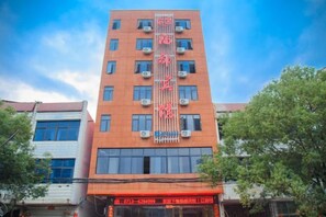 A multi-story building with a prominent vertical sign and multiple air conditioning units. - Fudu Hotel (Wuxue)
