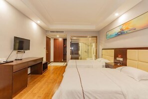 Una habitación de hotel con dos camas, un escritorio, un televisor y un cuadro en la pared.