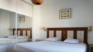 Habitación de hotel con una cama grande, una mesita de noche, un espejo y un certificado enmarcado en la pared.