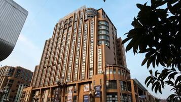 A tall, multi-story hotel with a curved corner design, featuring a series of windows and balconies.
