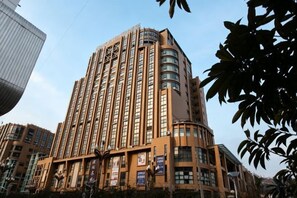 Un grand hôtel à plusieurs étages, doté d’une conception originale avec un coin arrondi, et caractérisé par une série de fenêtres et de balcons.