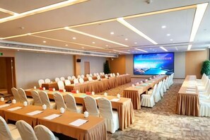 Une salle de conférence équipée de longues tables, de chaises et d’un grand écran.