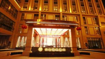 A hotel entrance with a large sign, a reception desk, and a building facade with multiple windows.