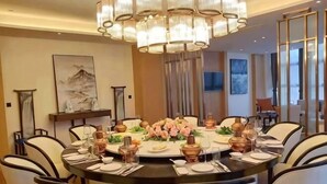 Uma sala de jantar com uma mesa redonda, cadeiras e um candelabro.