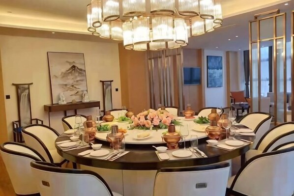 Un espace repas comprenant une table ronde, des chaises et un lustre.