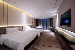 A modern hotel room with two beds, a flat-screen TV, a desk, and a large window.