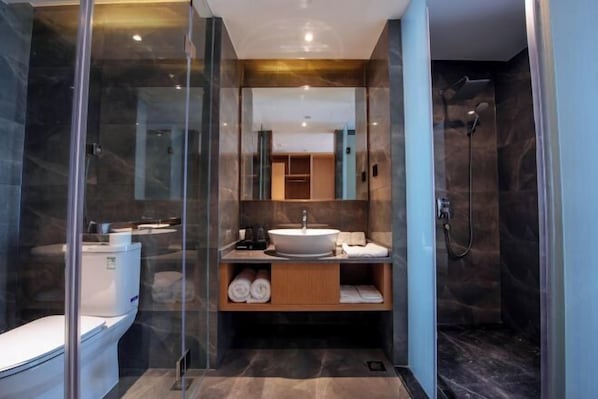 Une salle de bain moderne avec une douche en verre, un lavabo blanc et un sol carrelé en marbre.