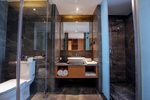 A modern bathroom with a glass-enclosed shower, a white sink, and a marble-tiled floor.