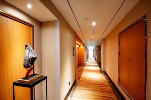 Un couloir d’hôtel avec des portes en bois et un sol recouvert de moquette.