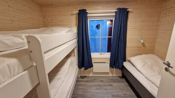 A small, wooden cabin room with bunk beds and a window with curtains.
