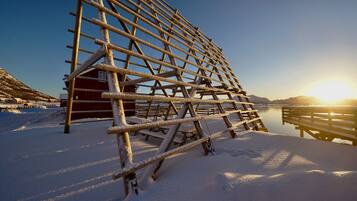 A wooden structure in a snowy landscape with a red building in the background.