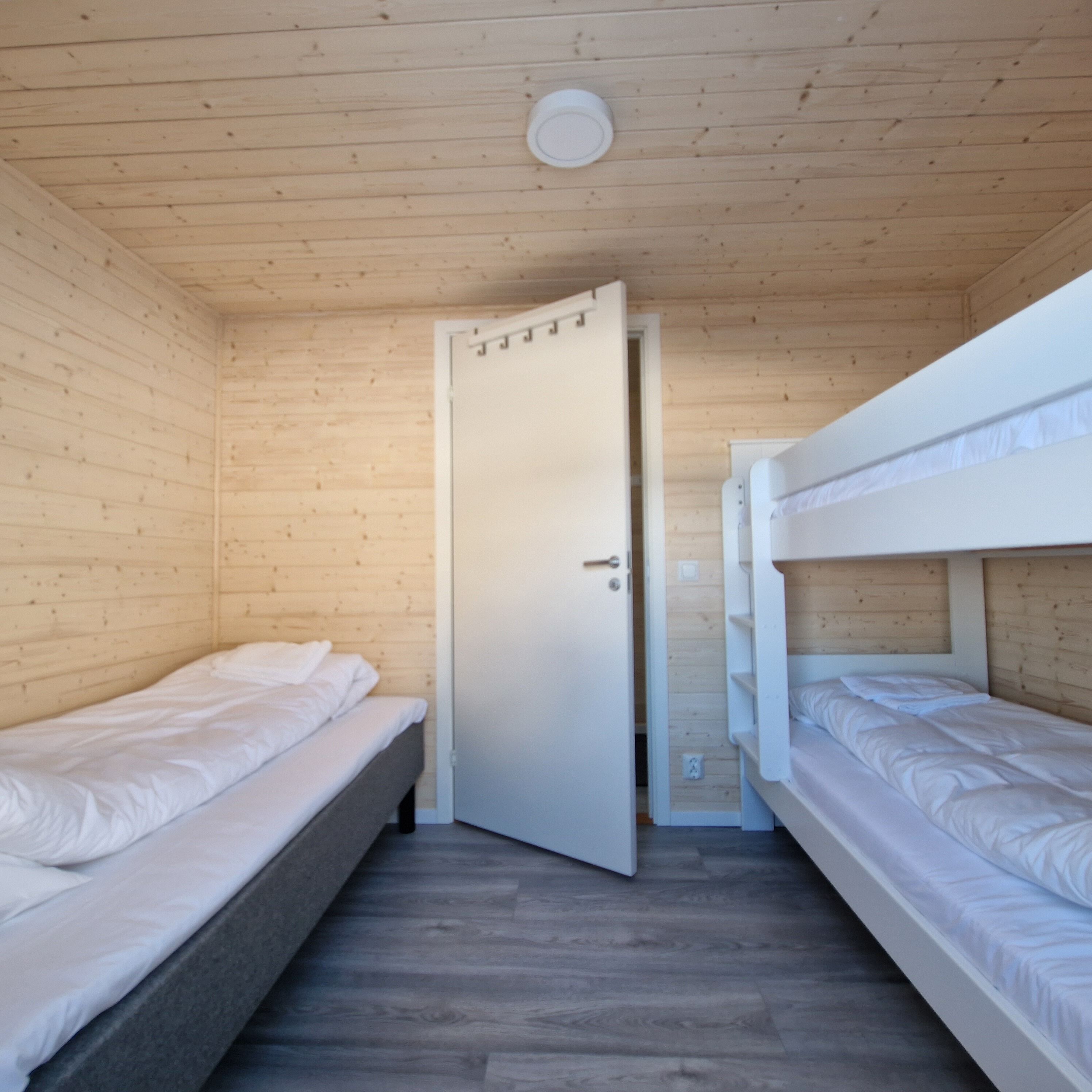 A compact room with two bunk beds and a door leading to another room.