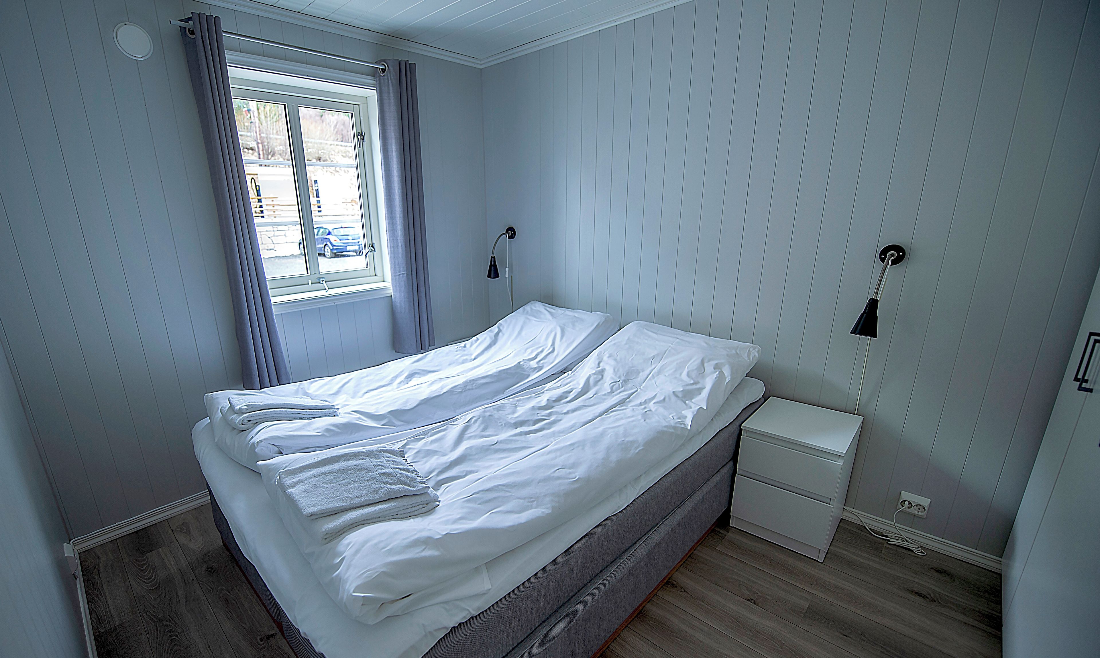 A bedroom on the first floor with an ocean view, featuring a bed, bedside tables, and a window with curtains.
