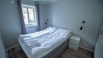 Ein Schlafzimmer im ersten Stock mit Meerblick, ausgestattet mit einem Bett, Nachttischen und einem Fenster mit Vorhängen.