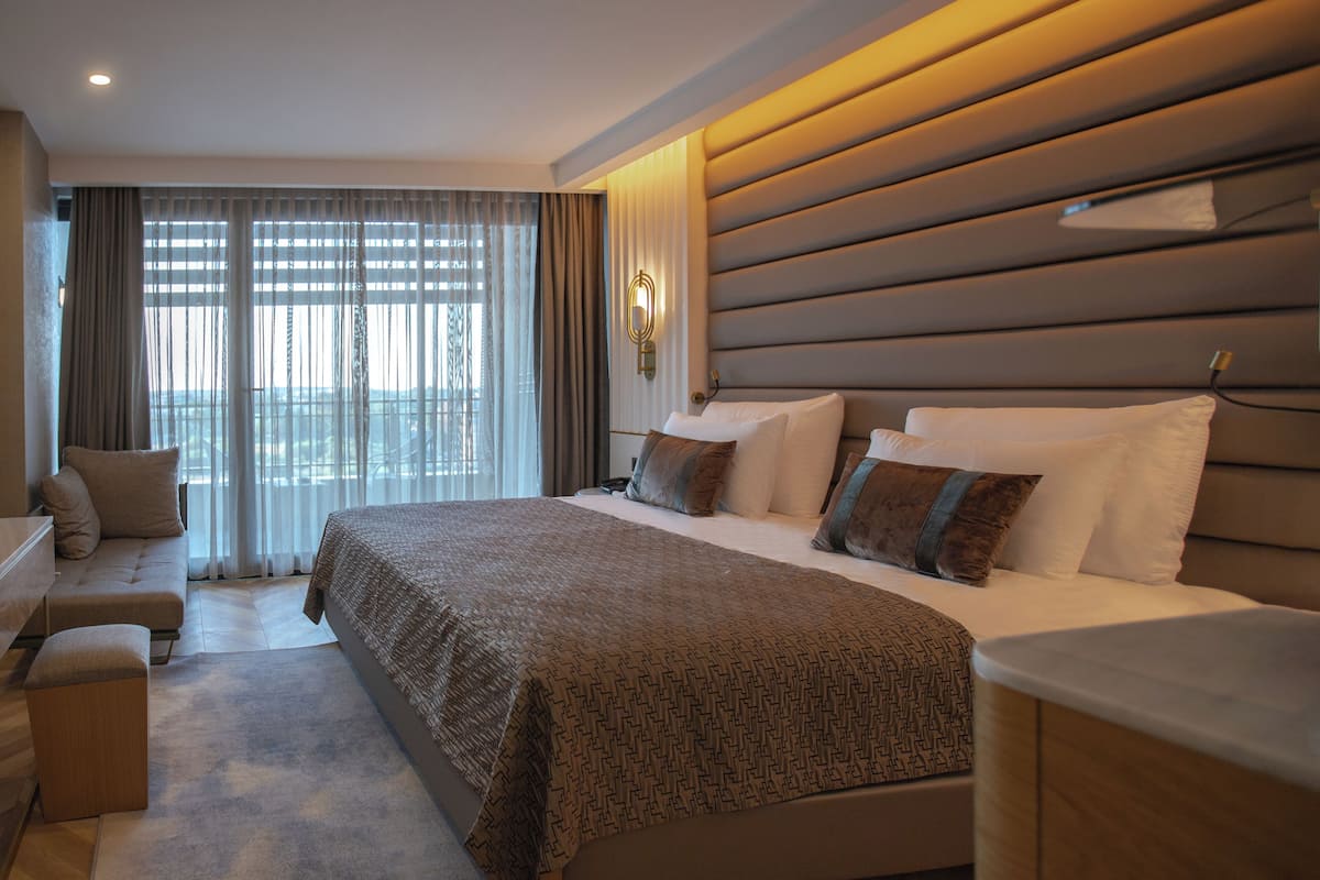 A hotel room with a large bed, a sofa, and a desk.