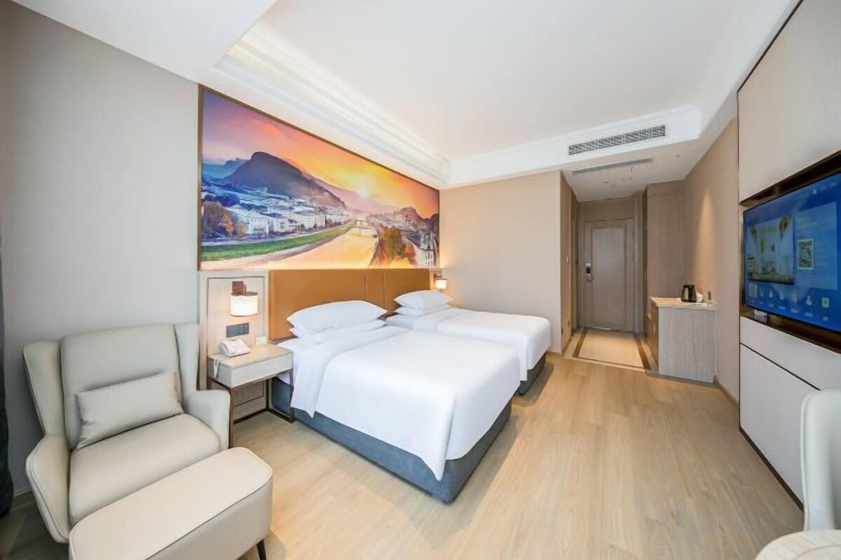 A hotel room with a bed, a chair, a desk, and a TV.