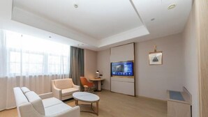Una habitación de hotel moderna con sofá, sillón, mesita y televisor.