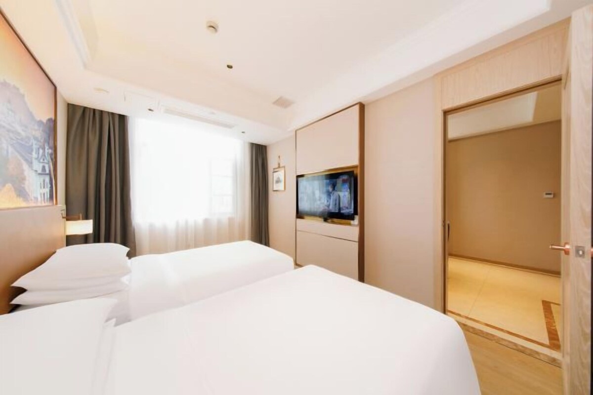 A hotel room with two beds, a TV, a wardrobe, and a painting on the wall.