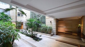 Un espacio interior moderno con un jardín central, una pared de vidrio y una recepción.