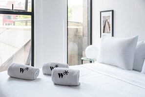 A hotel room with a large window, a bed with white bedding, and two towels with a logo on them. - w* | Welcoming 2BR in Roma Norte (Ciudad de México)
