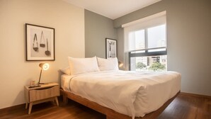 A bedroom with a wooden bed, a nightstand with a lamp, and framed artwork on the wall.