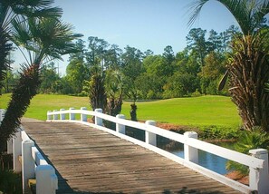 A wooden bridge with white railings leading to a golf course. - Brunswick Plantation Resort and Golf Villa 2705L in the Heart of NC Seafood Country by RedAwning (Calabash)