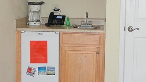 A compact kitchen with a microwave, coffee maker, and a refrigerator.