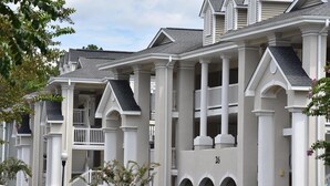 A multi-story residential building with a symmetrical facade, large windows, and a central entrance with a staircase.