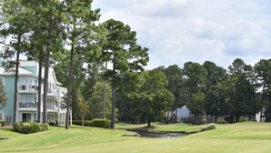 Un campo de golf con club house y un estanque.