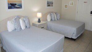 A hotel room with two beds, a nightstand with a lamp, and a door with a 'No Smoking' sign. - 2609l Home by RedAwning (Calabash)