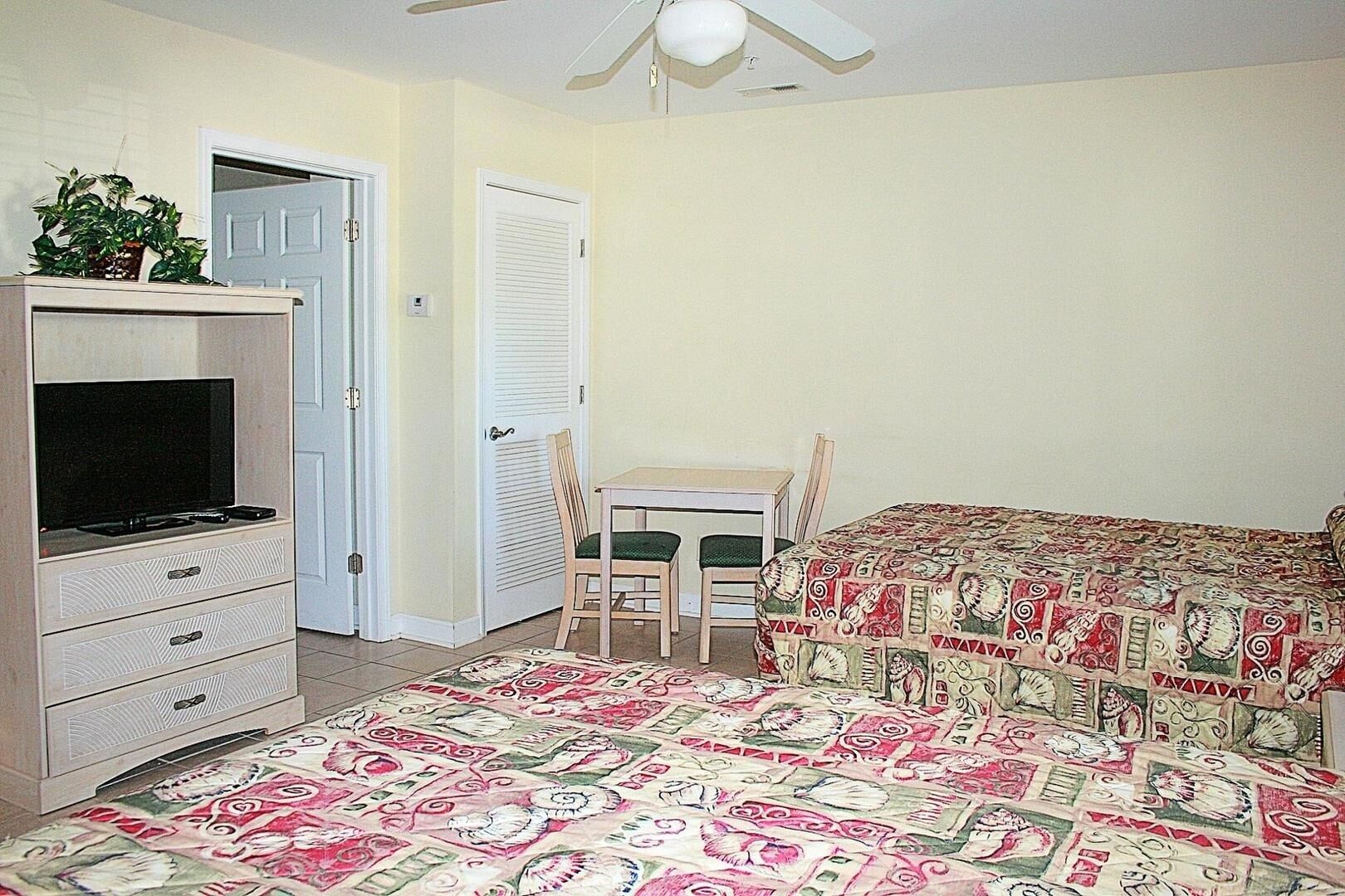 A bedroom with a bed, a TV, a desk, and a chair.