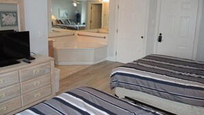 A hotel room with a bed, a TV, a dresser, a mirror, and a bathroom with a bathtub and shower. - 27 Holes of Golf Surrounds the Home 101l With Resort Amenities by Redawning (Calabash)