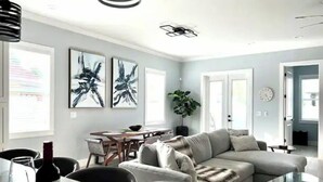 Ein modernes Wohnzimmer mit einer Couch, einem Glastisch und einem Essbereich mit Tisch und Stühlen.