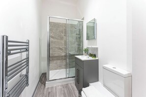 Ein modernes Badezimmer mit Duschkabine aus Glas, einem Waschtisch mit Spiegel und einer Toilette.