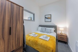 Une chambre d’hôtel avec un lit, une armoire, une table de chevet avec une lampe et un tableau au mur.