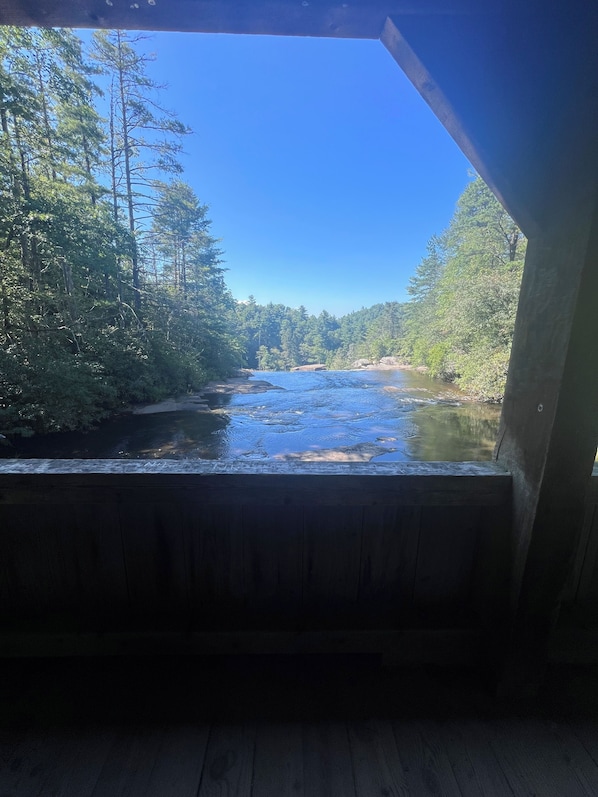 A wooden cabin with a view of a river and forest.