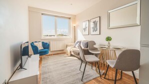 Een moderne woonkamer met een bank, stoelen, een eettafel en een groot raam.