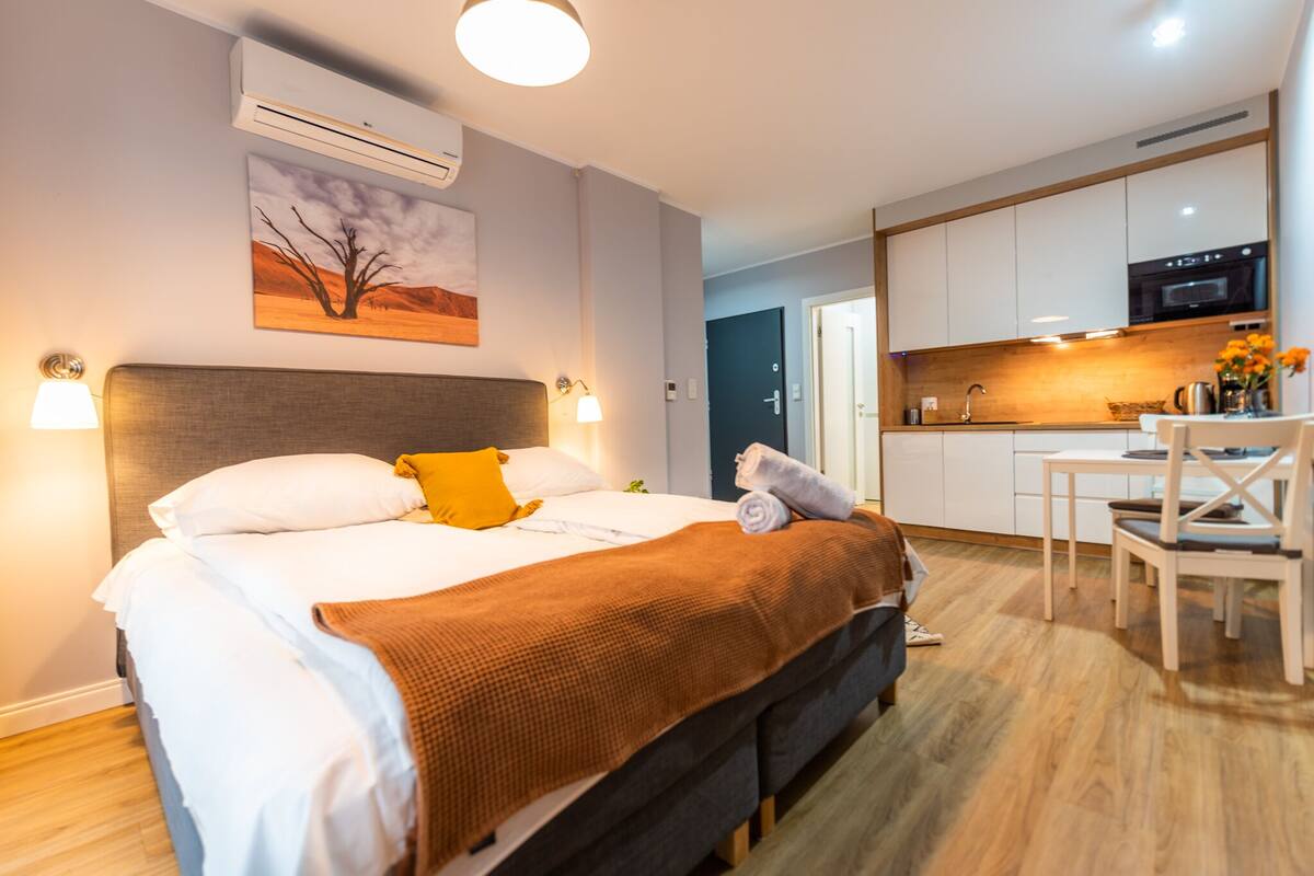 Une chambre d’hôtel moderne équipée d’un grand lit, d’un bureau et d’une kitchenette.