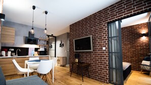 A modern kitchen with a wooden countertop, white chairs, and hanging pendant lights. - City Lights Kazimierz (Kraków)