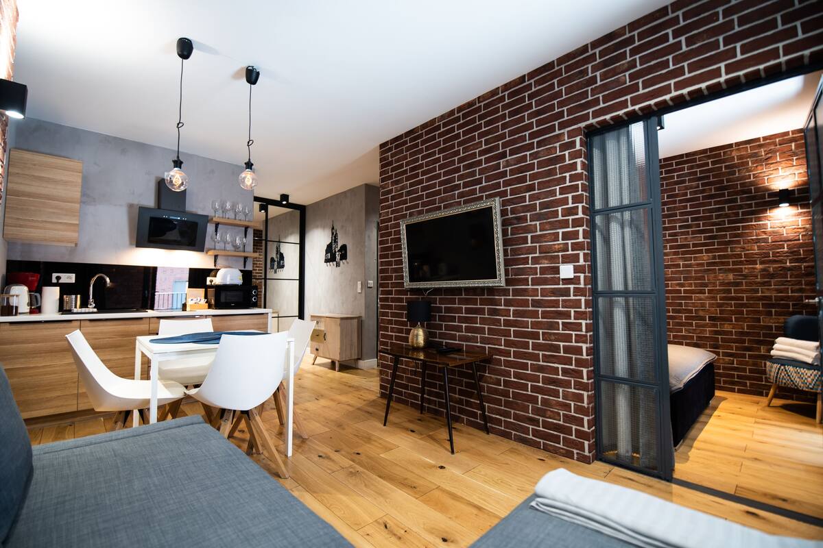 Une cuisine moderne avec un plan de travail en bois, des chaises blanches et des luminaires suspendus.