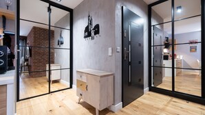 A modern kitchen with wooden flooring, a built-in cabinet, and a black refrigerator. - City Lights Kazimierz (Kraków)