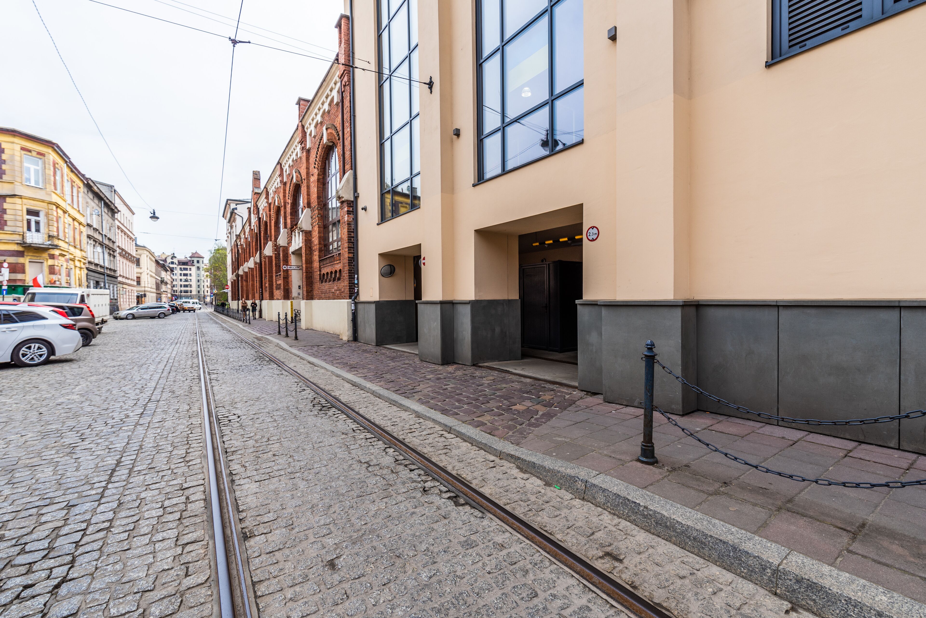 Una calle con tranvía, edificios con amplios ventanales y una barrera de cadena.