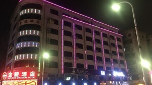 A hotel with multiple floors, illuminated by pink and white lights, and a sign indicating it is the Golden Dragon Hotel. - Jinlong Hotel (Dongguan)