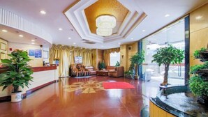 A hotel lobby with a reception desk, seating area, and a water feature. - Jinlong Hotel (Dongguan)