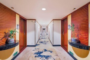 A hotel hallway with wooden paneling, a carpeted floor, and potted plants on the walls. - Jinlong Hotel (Dongguan)