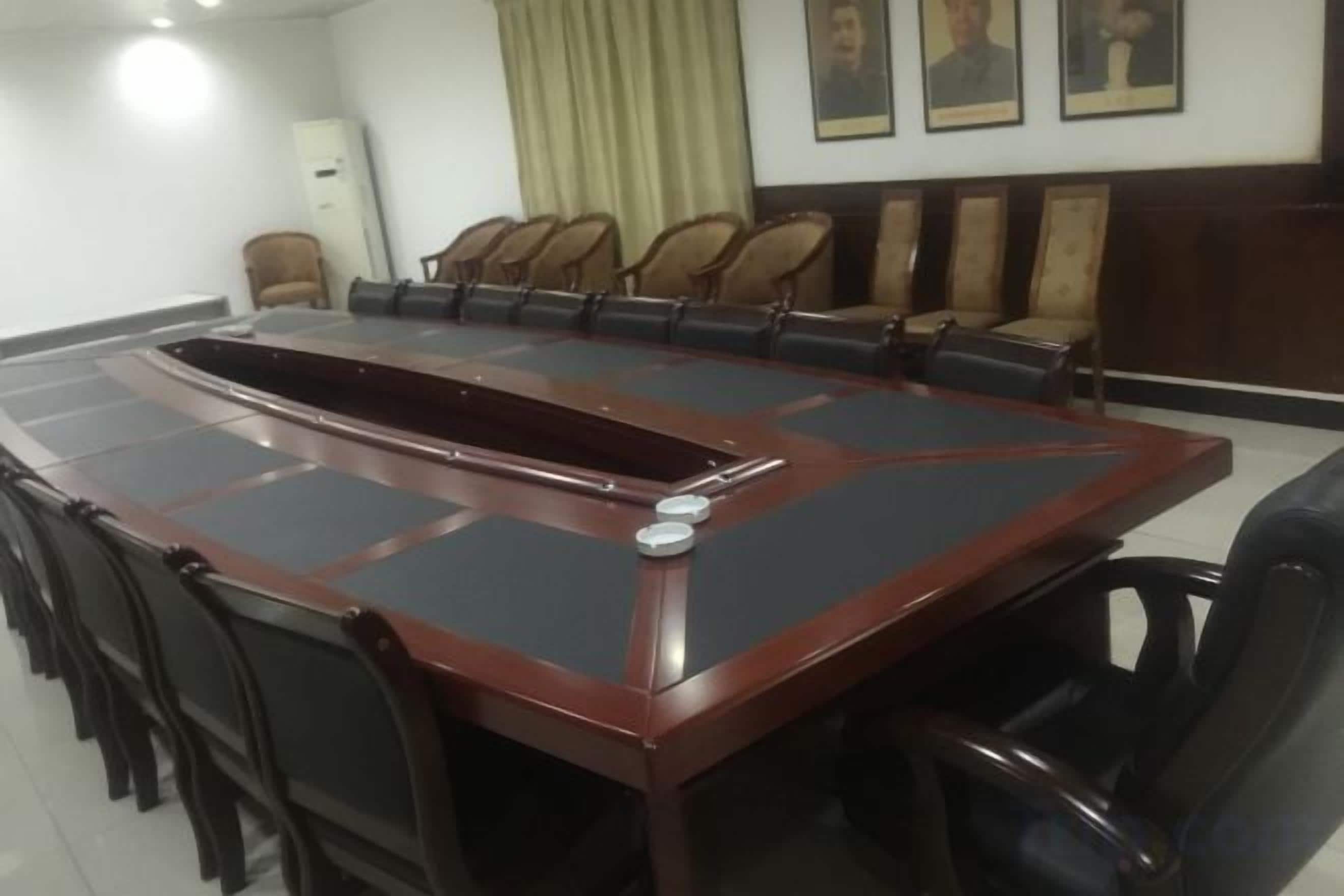 A conference room with a large oval table surrounded by chairs, a whiteboard, and a clock on the wall.
