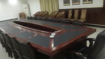 A conference room with a large oval table surrounded by chairs, a whiteboard, and a clock on the wall.