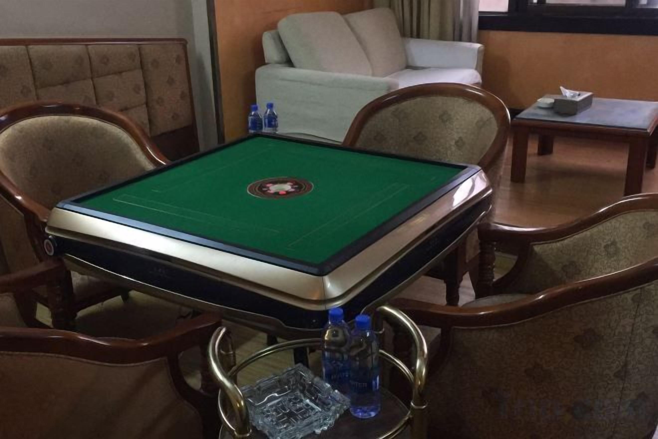 Una mesa de billar con superficie de fieltro verde, rodeada de sillas de madera con reposabrazos.