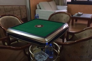 Una mesa de billar con superficie de fieltro verde, rodeada de sillas de madera con reposabrazos.